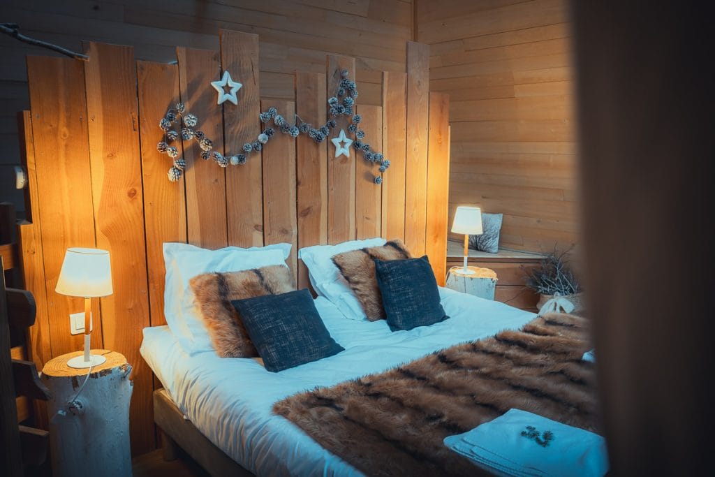 Chambre de cabane perchée avec lit double, décoration en bois et vue sur la forêt