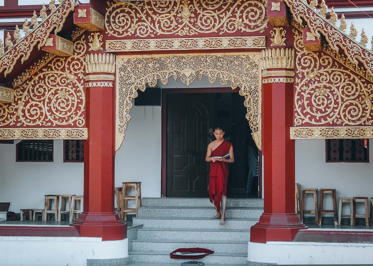 moine descendant les marches d'un temple en thailande