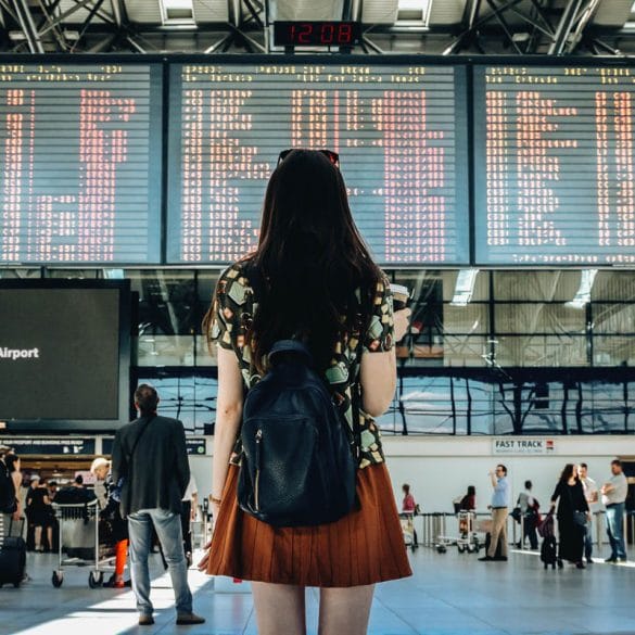 Voyageuse consultant le tableau des vols à l'aéroport, symbole de l'imprévu en voyage